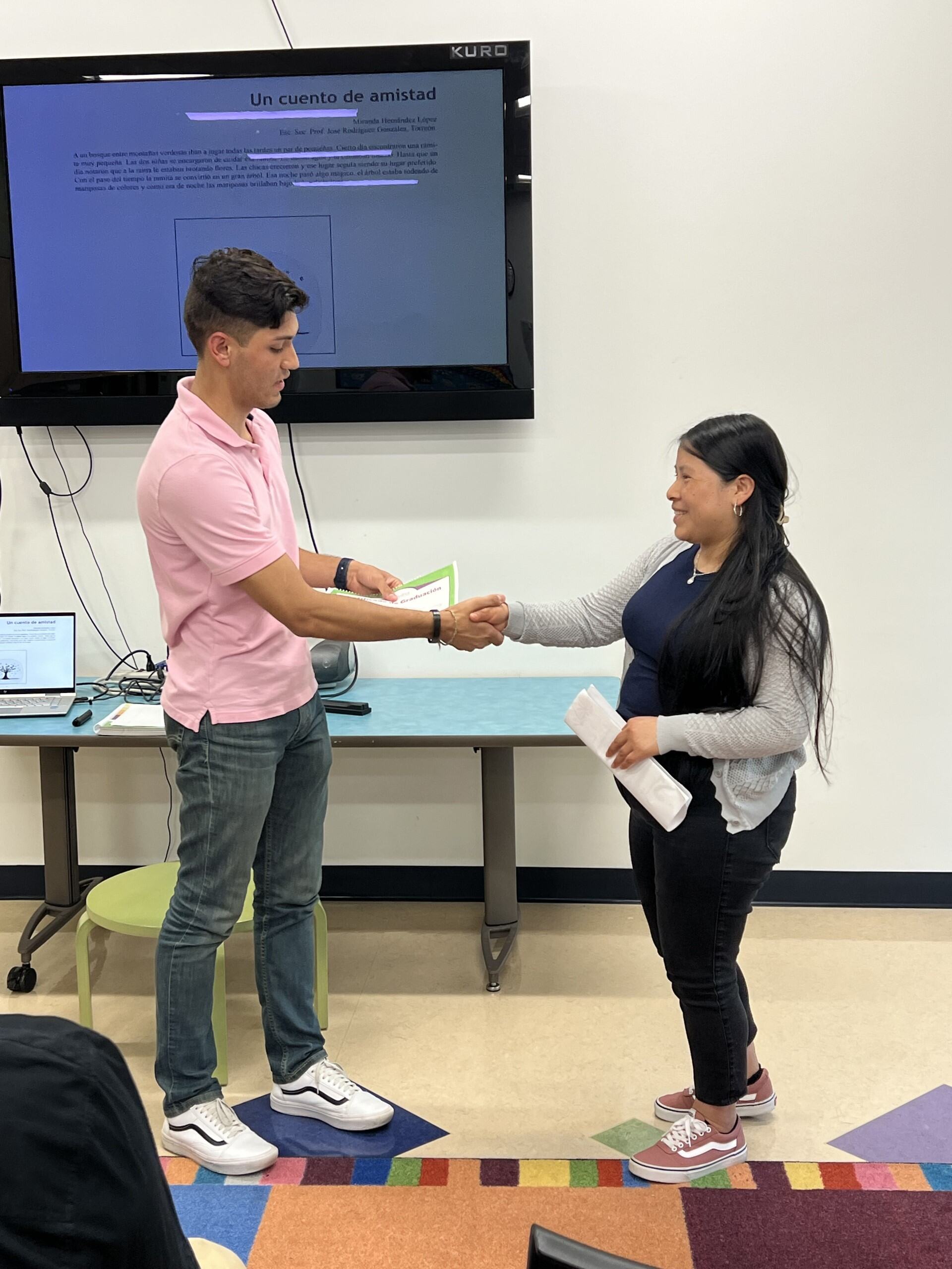 Male and female at front of room shaking hands