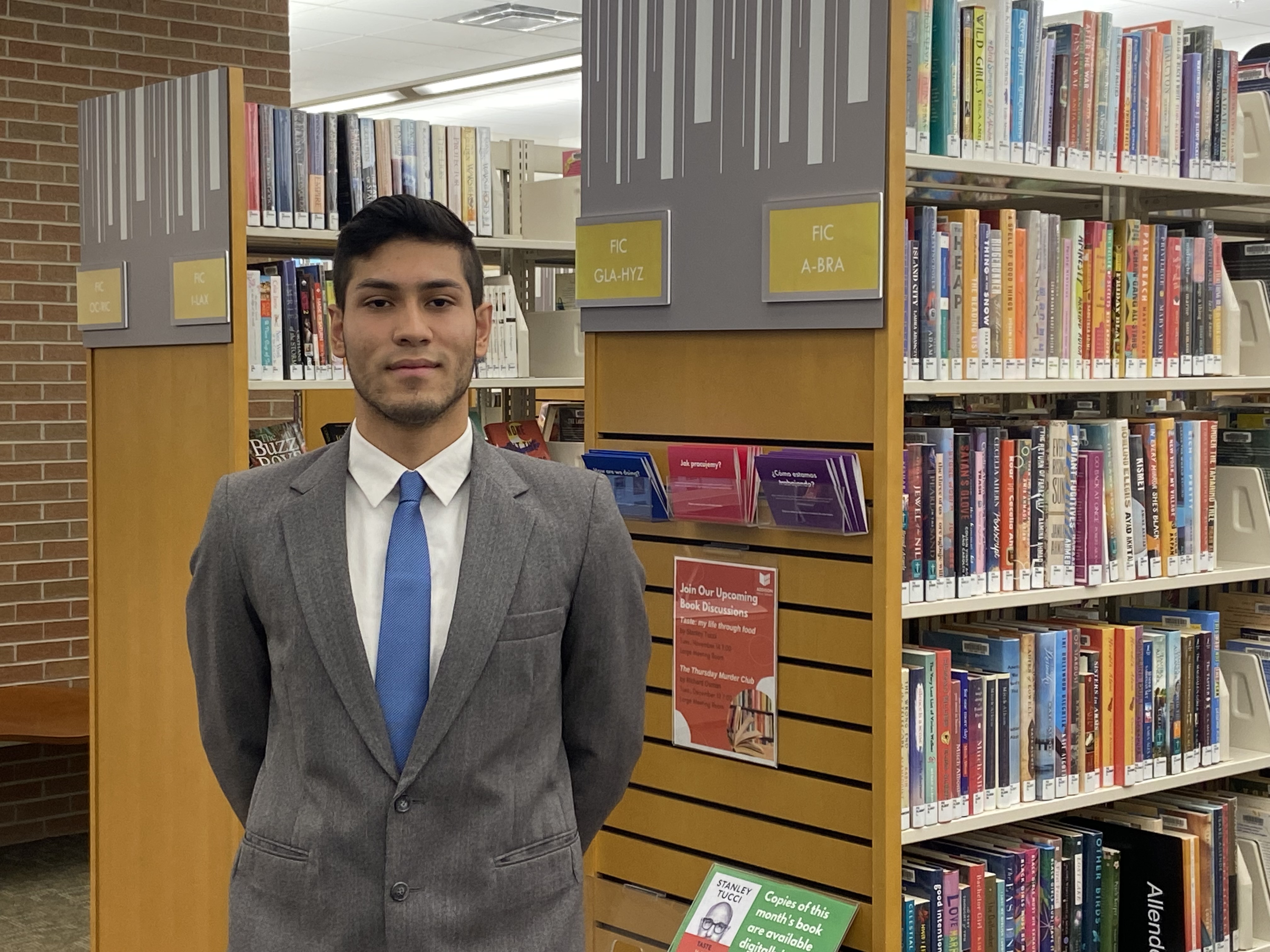 Young man standing in front of library bookcases