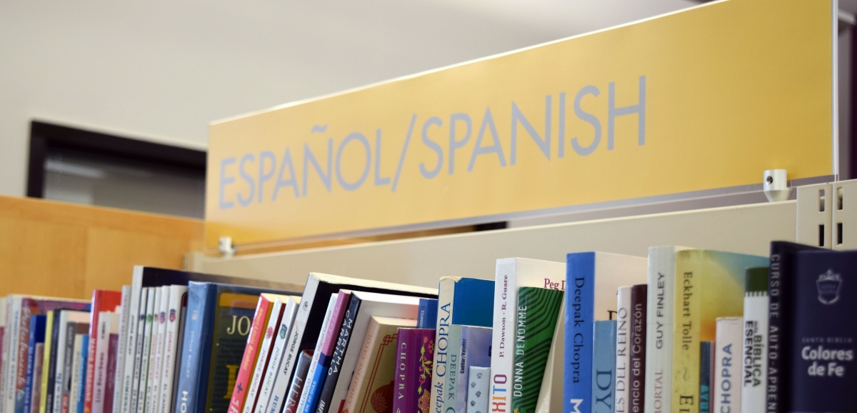 Photo of library book shelf. Labe for bookshelf reads "Espanol/Spanish" with a row of books underneath.