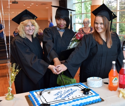 Photo of 3 graduates cutting cake