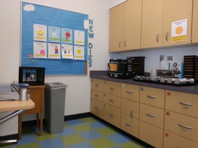 Small room with cabinets, laminator, and Ellison die cut machine.