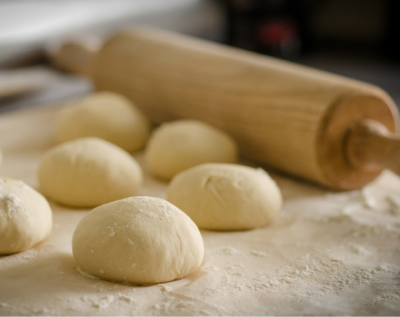 wooden rolling pin and dough balls on a kitchen counter