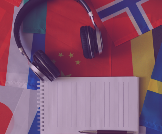 Photo of notebook, pencil, and headphones sitting on top of country flags