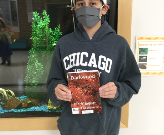 Photo of Yusuf Keshavarzi holding his book "Darkwood: Black Jaguar"