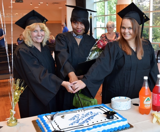 Photo of 3 graduates cutting cake