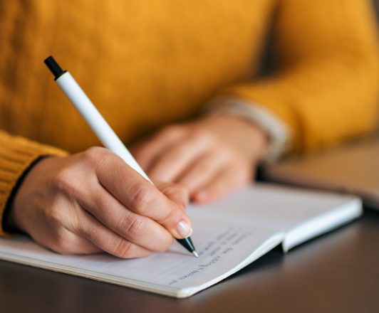 Stock photo. Close up of notebook with someone writing with a pen.