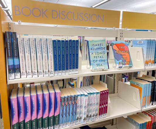 Photo of "Book Discussion" shelves located on the 2nd Floor. Shelves holding several rows of books.