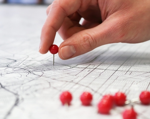 Hand placing a pin on a map.