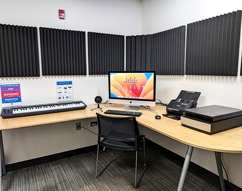 Photo of Sound Studio. The Sound Studio is a small room with a table and iMac. On the table is a piano keyboard, microphone, flatbed scanner, and document feeder.