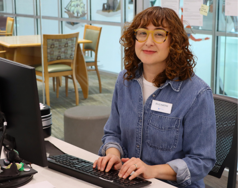 woman smiling behind computer at desk